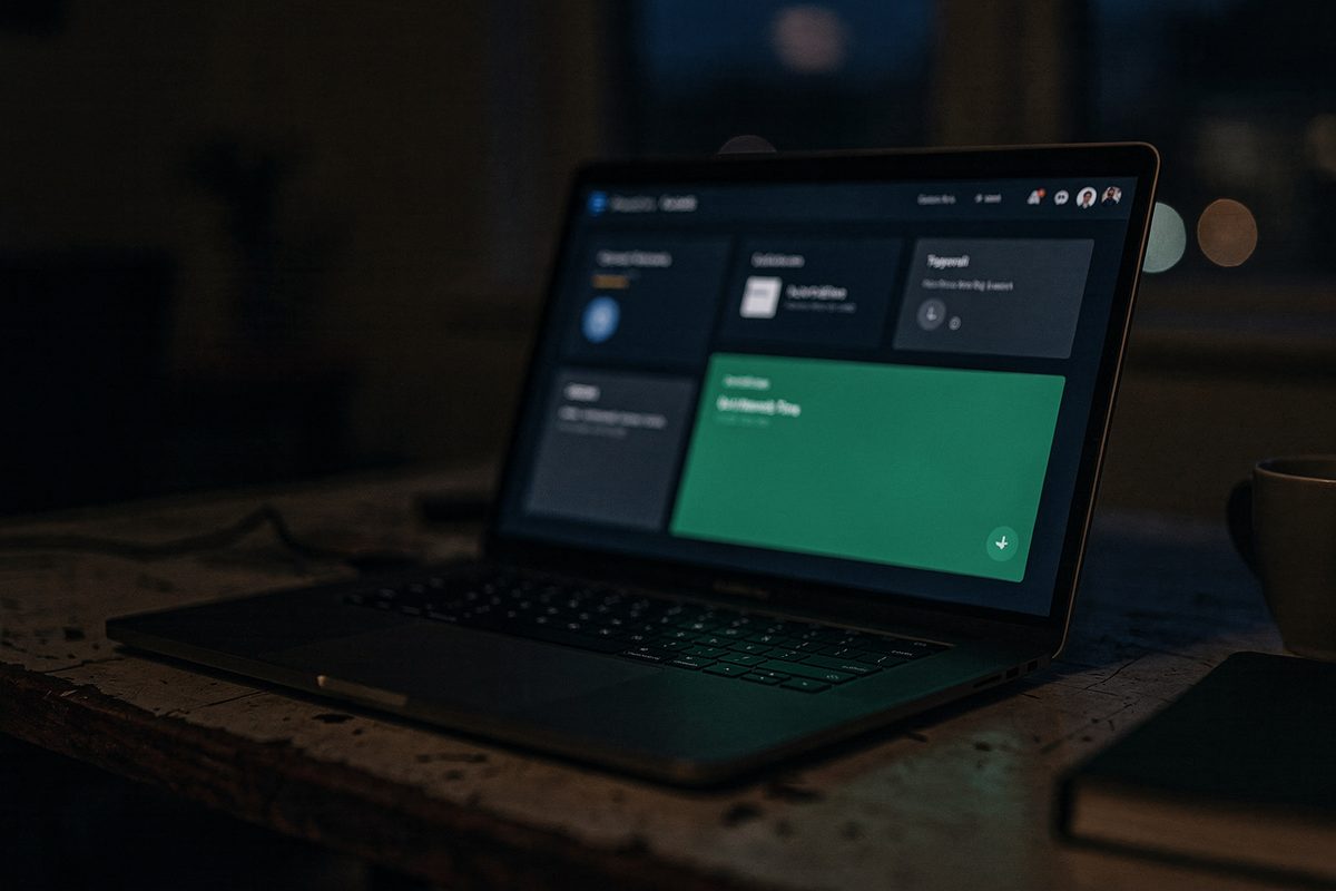 A laptop screen at night showing a dashboard with scene and usage panels highlighted in emerald