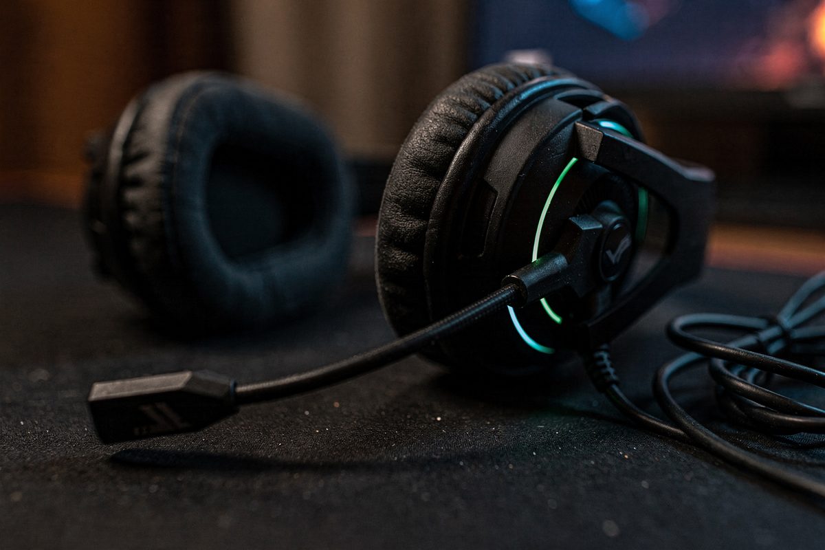 A macro detail shot of a gaming headset earcup and microphone boom on a dark desk